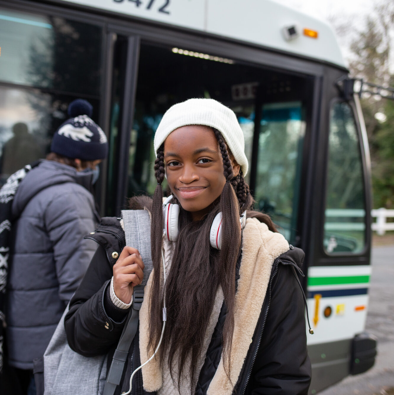 Happy girl in front of BC Transit bus ready to go to school